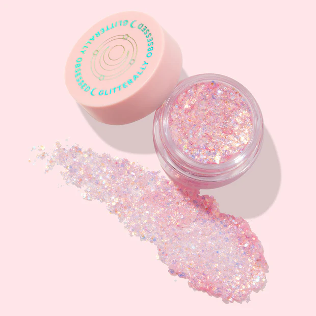 Open jar of pink Sailor Moon glitter gel with holographic sparkles and product spilled beside it.
